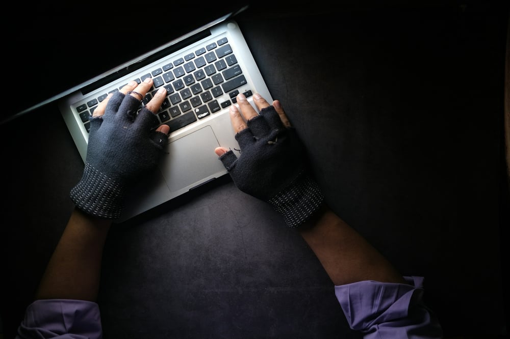 gloved hands on keyboard in a dimly lit room